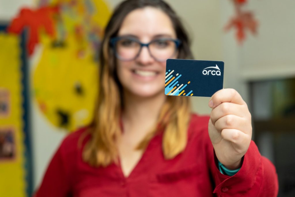 person smiling and holding ORCA card