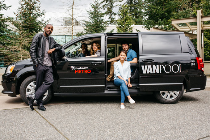 A group of young people sitting inside of a parked vanpool van
